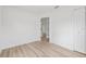 Clean, minimalist bedroom with light wood flooring and white walls, leading to a connecting room at 2233 Rightaway Ln, Plant City, FL 33565