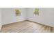 Bright bedroom featuring light wood floors and two windows providing ample natural light at 2233 Rightaway Ln, Plant City, FL 33565