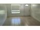 Bright living room featuring neutral tile flooring, a window with blinds, and a white front door at 2603 Mary Sue Sw St, Largo, FL 33774