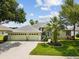 Charming single-story home with a well-manicured lawn, palm trees, and a three-car garage at 2730 River Woods Dr, Parrish, FL 34219