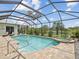 Sparkling screened-in pool and hot tub with patio space, lush greenery, and a view of the lake at 2730 River Woods Dr, Parrish, FL 34219