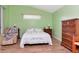 Cozy bedroom with green walls, wood floors, a floral comforter, and a quaint chair at 30445 Tremont Dr, Wesley Chapel, FL 33543