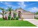 Charming home featuring a two-car garage and beautifully landscaped front yard with palm trees, perfect for curb appeal at 30445 Tremont Dr, Wesley Chapel, FL 33543