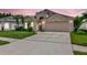 Charming home featuring a two-car garage and beautifully landscaped front yard with palm trees, perfect for curb appeal at 30445 Tremont Dr, Wesley Chapel, FL 33543