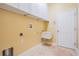 Functional laundry room featuring upper cabinets, sink, and travertine flooring at 31331 Anniston Dr, Wesley Chapel, FL 33543