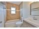 Tiled bathroom featuring a tub, toilet, and modern vanity with a large mirror and natural light at 3209 W Tyson Ave, Tampa, FL 33611