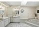 Bright bathroom featuring double sinks, ample cabinetry, tiled floor, and a relaxing soaking tub at 3936 Crooked Island Dr, Punta Gorda, FL 33950