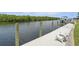 Waterfront property featuring a concrete boat dock and chairs, great for enjoying the views by the water at 3936 Crooked Island Dr, Punta Gorda, FL 33950