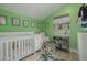 Bedroom with green walls, white crib, comfortable glider, and plenty of light at 4100 Miramar Way, St Petersburg, FL 33705
