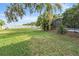Expansive backyard with lush green grass and view of pool and patio beyond the mature landscaping and towering trees at 6411 Barton Rd, Plant City, FL 33565