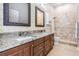 Modern bathroom with double sinks, granite counters, and tiled shower with glass door at 6411 Barton Rd, Plant City, FL 33565