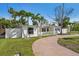 Landscaped yard with mature palm trees and a circular driveway of a charming single-story home at 709 Pruitt Dr, Madeira Beach, FL 33708