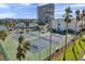 Exterior shot showing beautiful tennis courts surrounded by tropical palm trees at 7600 Sun Island S Dr # 407, South Pasadena, FL 33707