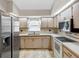 Well-lit kitchen with neutral cabinets, stainless steel refrigerator, and a double sink under a window at 7712 40Th N Ter, St Petersburg, FL 33709