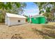 Backyard showcasing detached white structure with a green house in the background at 8215 N 14Th St, Tampa, FL 33604