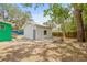 Backyard featuring a detached white structure with trees and a green building in the background at 8215 N 14Th St, Tampa, FL 33604