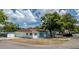 A cozy light blue house features a well-maintained lawn, a brown roof, and a secure chain-link fence at 8525 N Ola Ave, Tampa, FL 33604