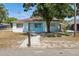 Charming single-story home featuring a light blue exterior, a cozy front yard, and a concrete walkway leading to the front door at 8525 N Ola Ave, Tampa, FL 33604