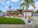 Charming single-story home with artificial grass, an American flag, and lush tropical landscaping at 1102 Goshen Rd, Tarpon Springs, FL 34689