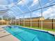 This bright pool area features lounge chairs, a wood fence and a glimpse of solar panels on a neighboring home at 1102 Goshen Rd, Tarpon Springs, FL 34689