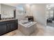 Bright bathroom featuring a luxurious soaking tub, dual sinks with dark vanities, and tile flooring at 11714 Sunburst Marble Rd, Riverview, FL 33579