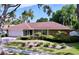 Charming front exterior with manicured landscaping, a stone accent wall, and an attached two-car garage at 13725 Oak Forest N Blvd, Seminole, FL 33776