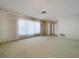 Spacious living room with carpeted floors, large windows, and neutral walls ready for personalization at 13725 Oak Forest N Blvd, Seminole, FL 33776