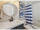 Updated bathroom with a stylish vanity, round mirror, and blue striped shower curtain at 1676 Arabian Ln, Palm Harbor, FL 34685