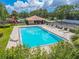 A community pool with lounge chairs is surrounded by a black fence and flowers with a covered area for shade and seating at 1807 Split Fork Dr, Oldsmar, FL 34677