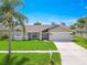 Charming single-story home featuring a lush green lawn, mature landscaping, and an attached two-car garage at 1838 Eagle Ridge Blvd, Palm Harbor, FL 34685