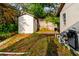 A storage shed and the side of a home in a backyard area with grass and equipment at 1974 Hidden Springs Pl, Clearwater, FL 33760
