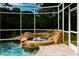 Close-up of rock waterfall flowing into an attached hot tub with tile accents beside the sparkling in-ground pool at 1974 Hidden Springs Pl, Clearwater, FL 33760
