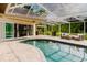 The home's outdoor screened-in living space features an outdoor cooking and relaxation area with a sparkling pool at 1974 Hidden Springs Pl, Clearwater, FL 33760