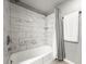 Bathroom tub and shower are newly tiled with a grey curtain and stainless steel fixtures at 2581 Countryside Blvd # 2309, Clearwater, FL 33761