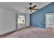 Bright bedroom with ceiling fan, neutral carpet, and large window bringing in natural light at 27440 Cedar Park Ct, Wesley Chapel, FL 33544
