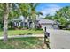Charming blue home featuring a three-car garage, well-manicured lawn, and lush landscaping at 27440 Cedar Park Ct, Wesley Chapel, FL 33544