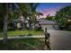Charming blue home featuring a three-car garage, well-manicured lawn, and lush landscaping at 27440 Cedar Park Ct, Wesley Chapel, FL 33544