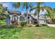 Charming blue home featuring a three-car garage, well-manicured lawn, and lush landscaping at 27440 Cedar Park Ct, Wesley Chapel, FL 33544