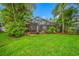 A lush backyard featuring a screened pool area, mature trees, and landscaping provides a private outdoor space at 3000 Naughton Way, Tarpon Springs, FL 34688