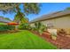 The backyard features beautiful landscaping, mulch and an orange umbrella over outdoor seating at 3000 Naughton Way, Tarpon Springs, FL 34688