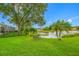This backyard offers a bench overlooking a pond with palm trees and lush landscaping, framed by a well-maintained lawn at 3000 Naughton Way, Tarpon Springs, FL 34688