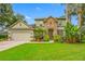 Inviting two-story home with stone facade, lush landscaping, and a well-manicured lawn at 3000 Naughton Way, Tarpon Springs, FL 34688