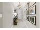 Inviting hallway with elegant light fixture, tile floors, decor table, and Gathering photos on the wall at 32193 Watoga Loop, Wesley Chapel, FL 33543
