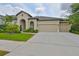 Stunning single-story home featuring a three-car garage, landscaped yard, and an arched entryway at 6016 Shadowlake Dr, Apollo Beach, FL 33572