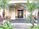 Elegant front entrance with a dark wood door, surrounded by tropical plants and lush greenery at 6801 S Sparkman St, Tampa, FL 33616
