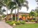 Charming single-story home featuring vibrant landscaping with palm trees, flowers, and a brick driveway at 6801 S Sparkman St, Tampa, FL 33616