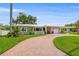 A cozy home with a curved brick driveway and lush green lawn, enhanced by tropical landscaping and a bright, cloudless sky at 715 45Th Ne Ave, St Petersburg, FL 33703