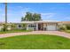 A cozy home with a curved brick driveway and lush green lawn, enhanced by tropical landscaping and a bright, cloudless sky at 715 45Th Ne Ave, St Petersburg, FL 33703