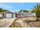 Exterior view of a gray home with a red front door, a palm tree, and a front lawn at 7411 Seashore Dr, Port Richey, FL 34668
