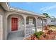 Home front entrance featuring a red door, gray stucco exterior and white accents at 7411 Seashore Dr, Port Richey, FL 34668